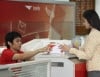 รูปพนักงานไปรษณีย์กำลังรับพัสดุมาจากลูกค้าเพื่อทำการชั่งน้ำหนัก